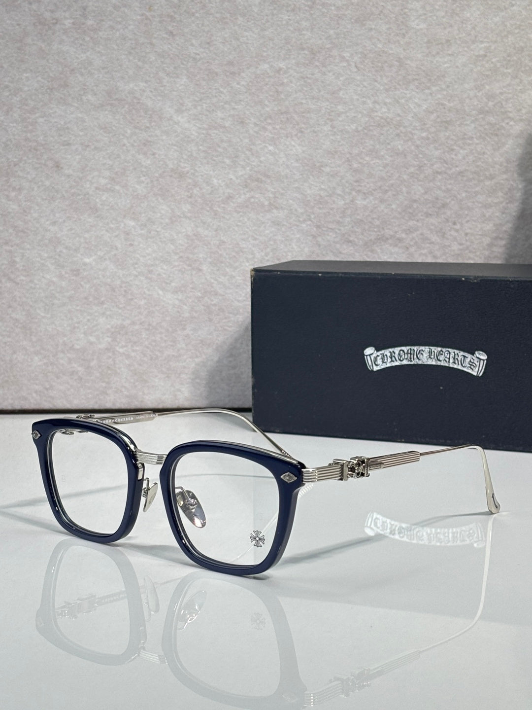 Dark blue eyeglasses with rectangular clear lenses and metal hinge hardware