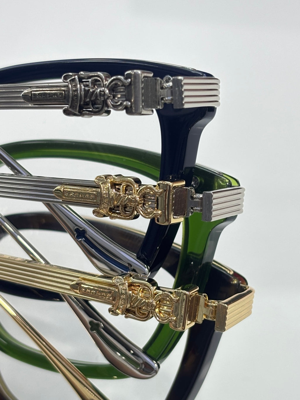 Close-up of eyeglasses temple hardware with chrome and gold ornate designs