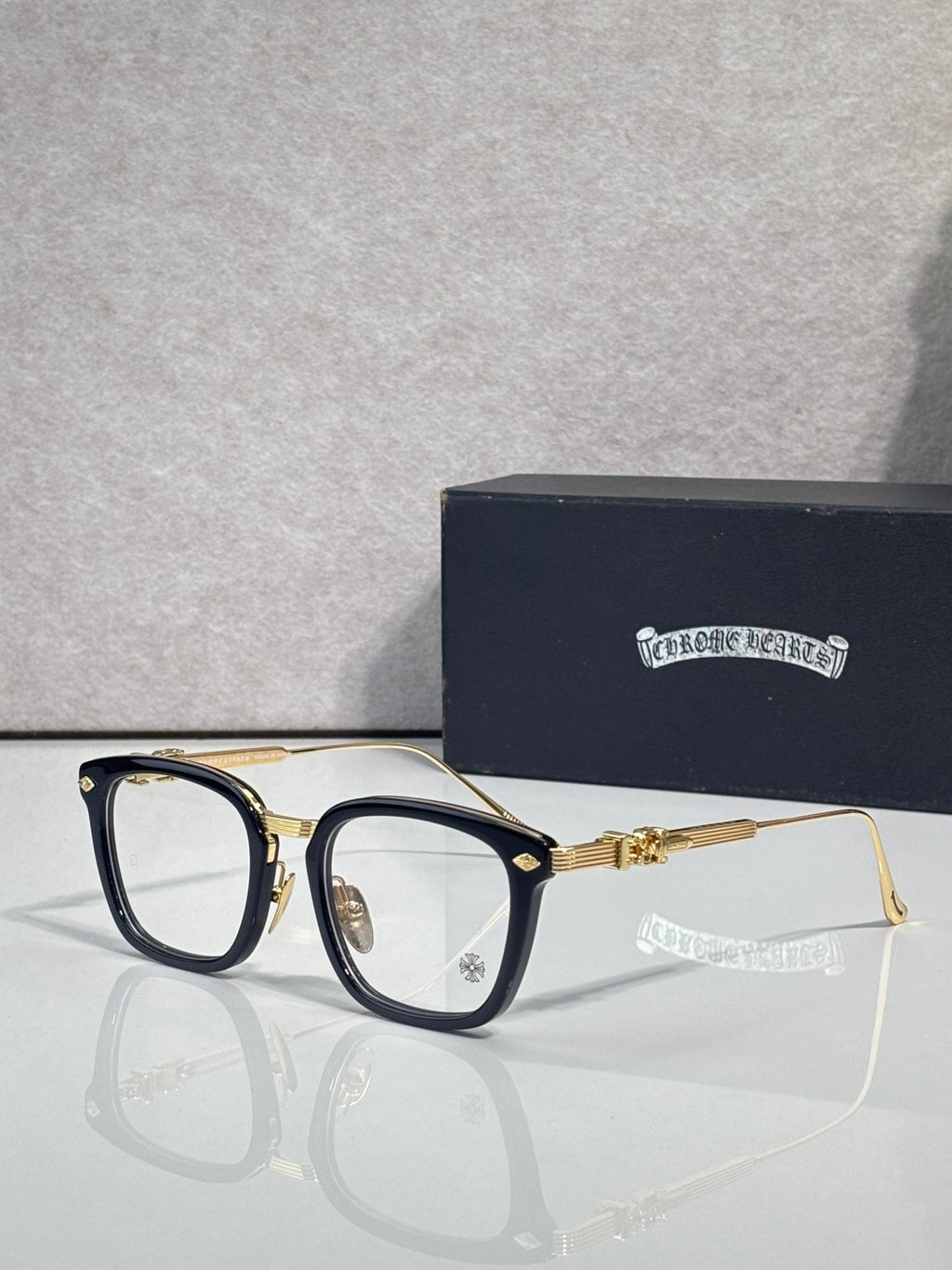 Black and gold eyeglasses with rectangular clear lenses and ornate temple hardware