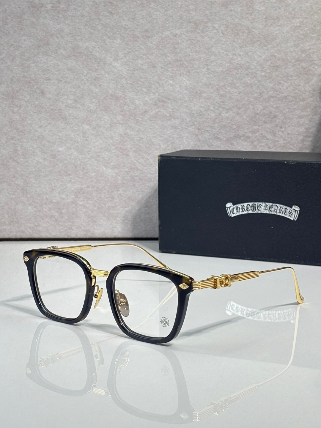 Gold eyeglasses with rectangular clear lenses, dark blue inner frame, and gold temples