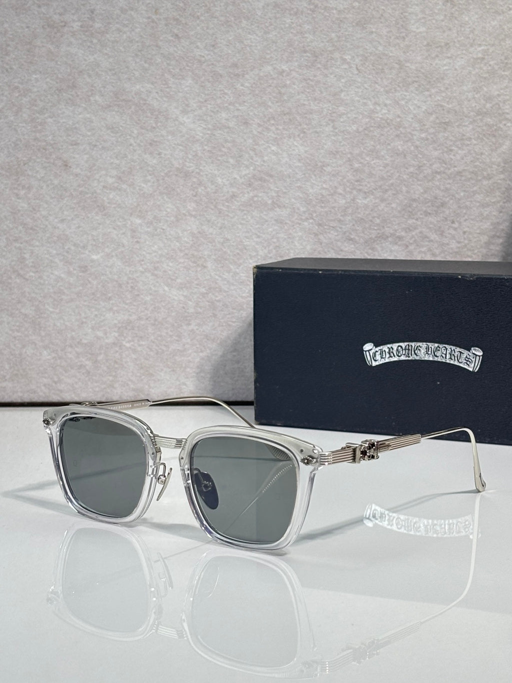 Round-corner square sunglasses with dark lenses, clear silver frame, chrome trim