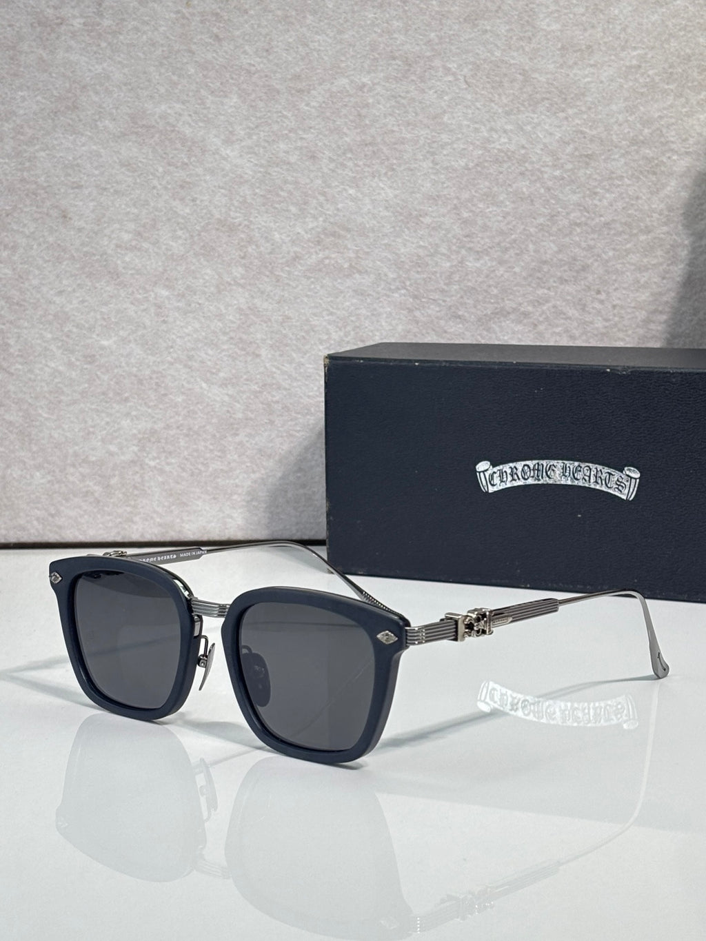 Square sunglasses with dark lenses, black frame, silver temple arms and gold details