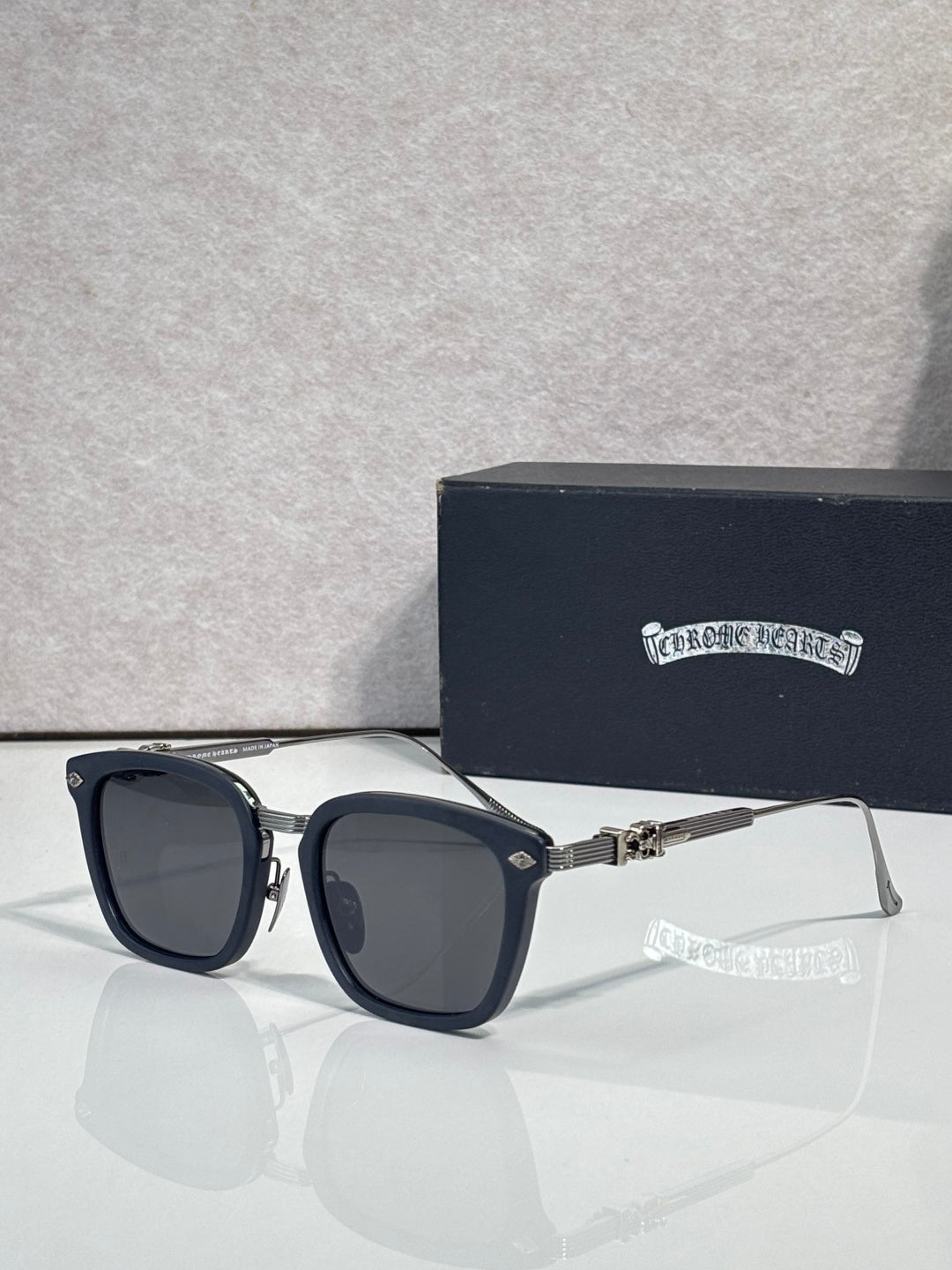 Square sunglasses with dark lenses, black frame, silver temple arms and gold details