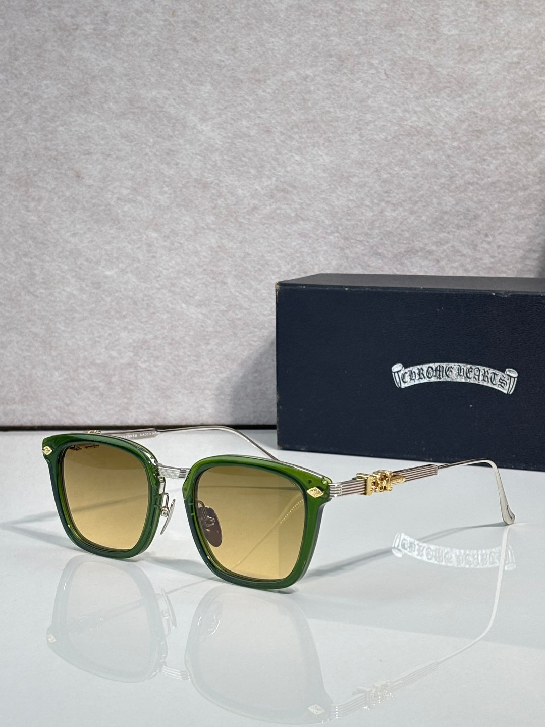 Square sunglasses with yellow-green lenses, green frame, gold bridge and chrome trim