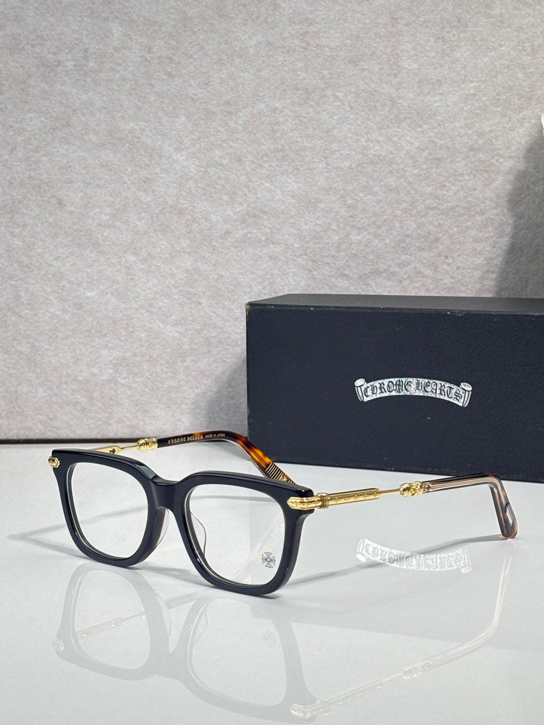 Black eyeglasses with gold metal temples and amber-tinted detail