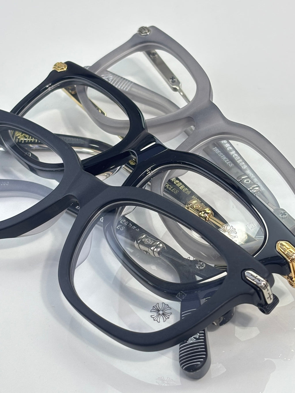 Assorted eyeglasses in navy and gray with gold accents and rectangular lenses