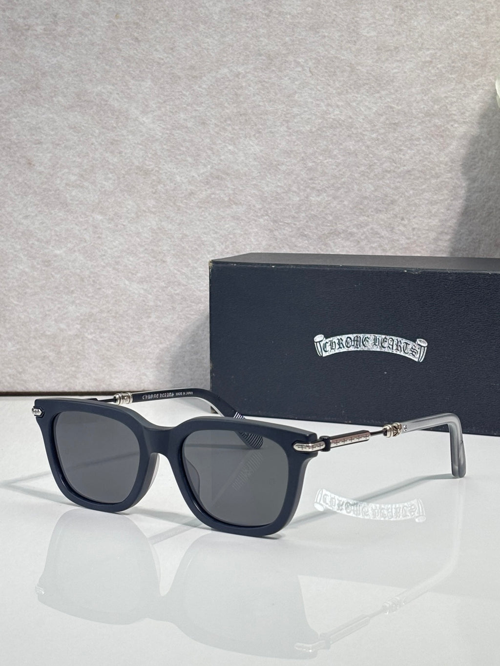 Glasses with dark frame, smoke-tinted lenses, metal bridge and gold tips