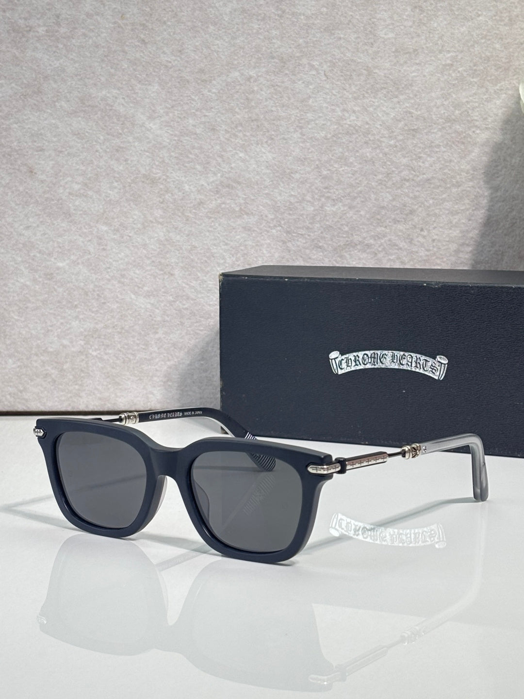 Glasses with dark frame, smoke-tinted lenses, metal bridge and gold tips