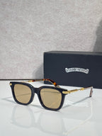 Chrome glasses with dark navy frame, amber-tinted lenses, gold accents