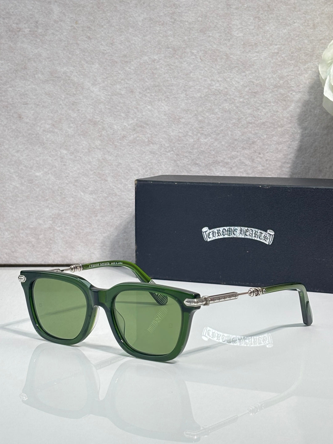 Glasses with green frames, green-tinted lenses, gold-tone metal hinges