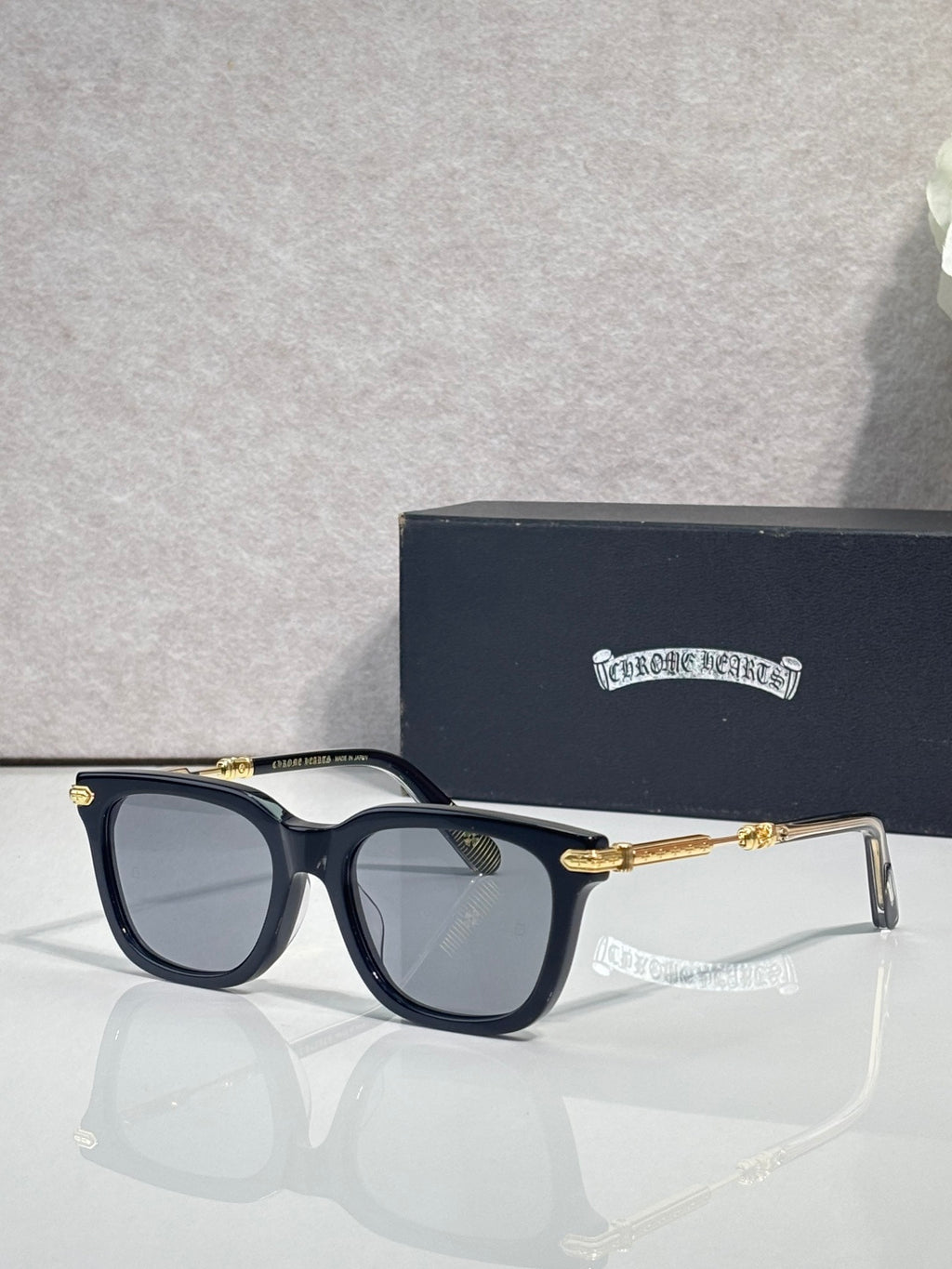 Glasses with dark navy frame, tinted lenses, gold-tone arms