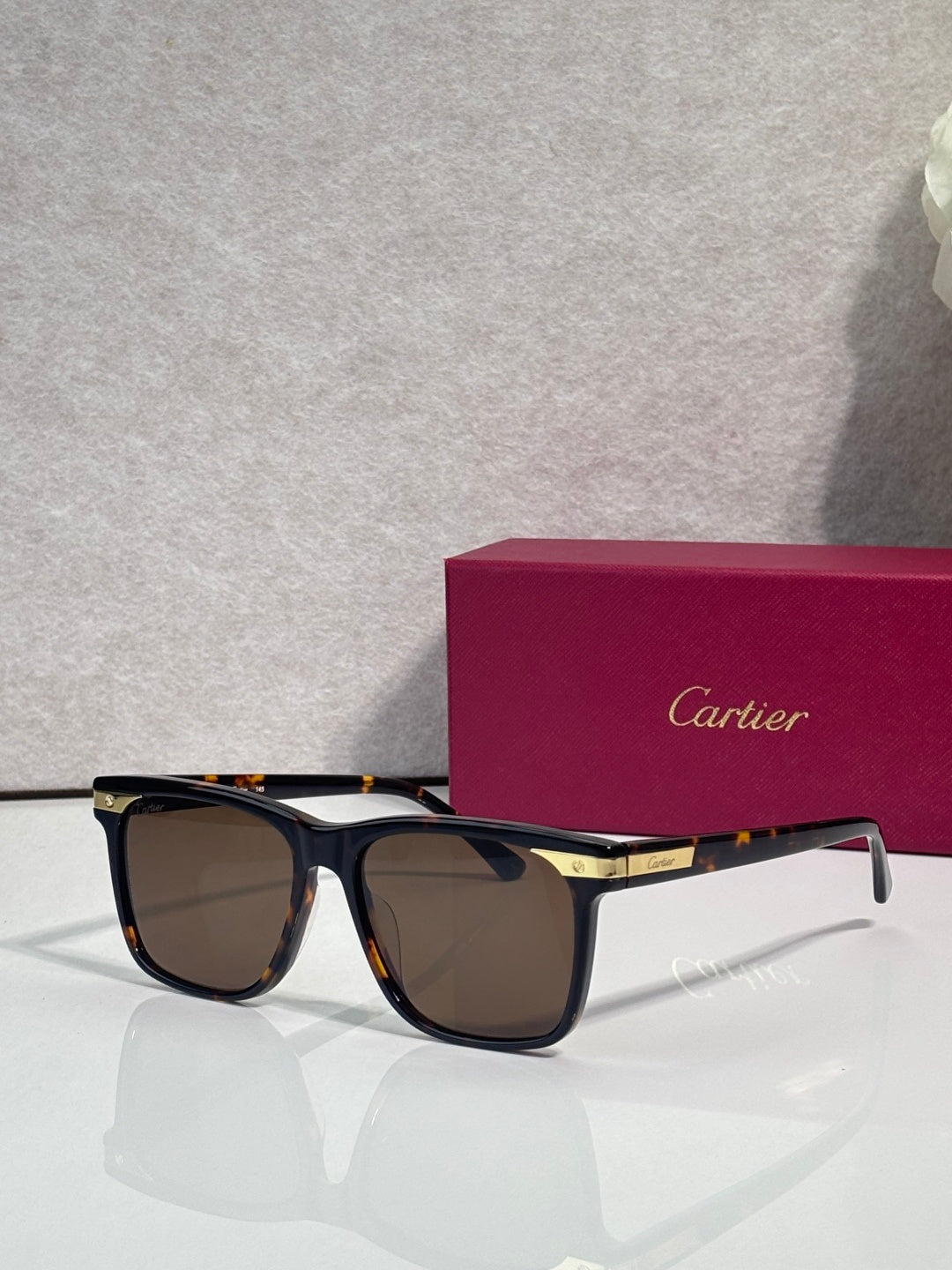 Sunglasses with dark frames, tinted lenses, and gold-trimmed bridge