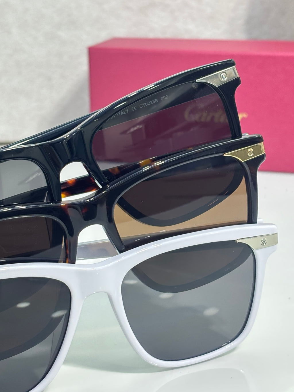 Sunglasses close-up with navy top frame, dark lenses, and Cartier logo plate