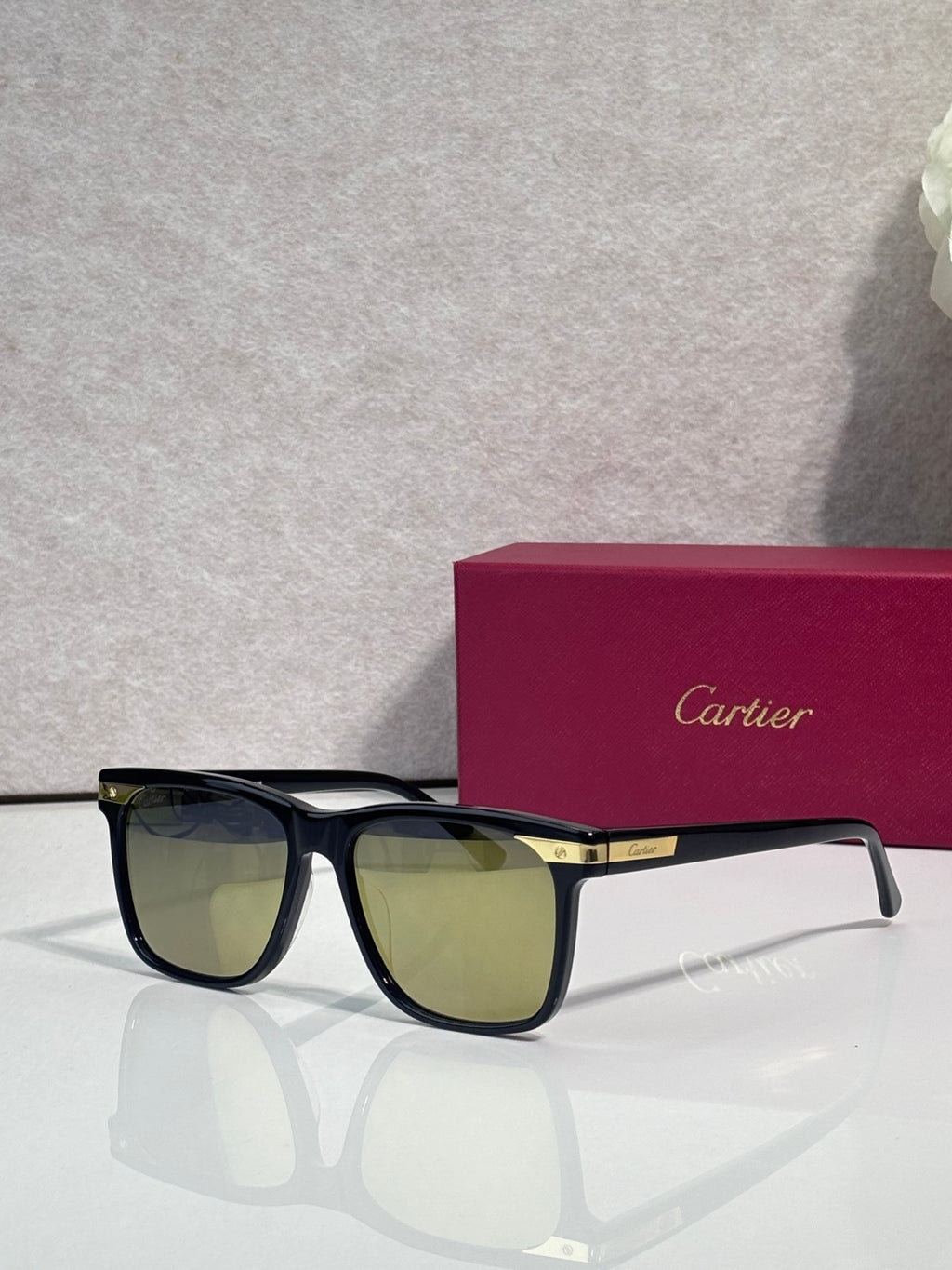Sunglasses with dark frames and olive-tinted lenses, gold logo plaque