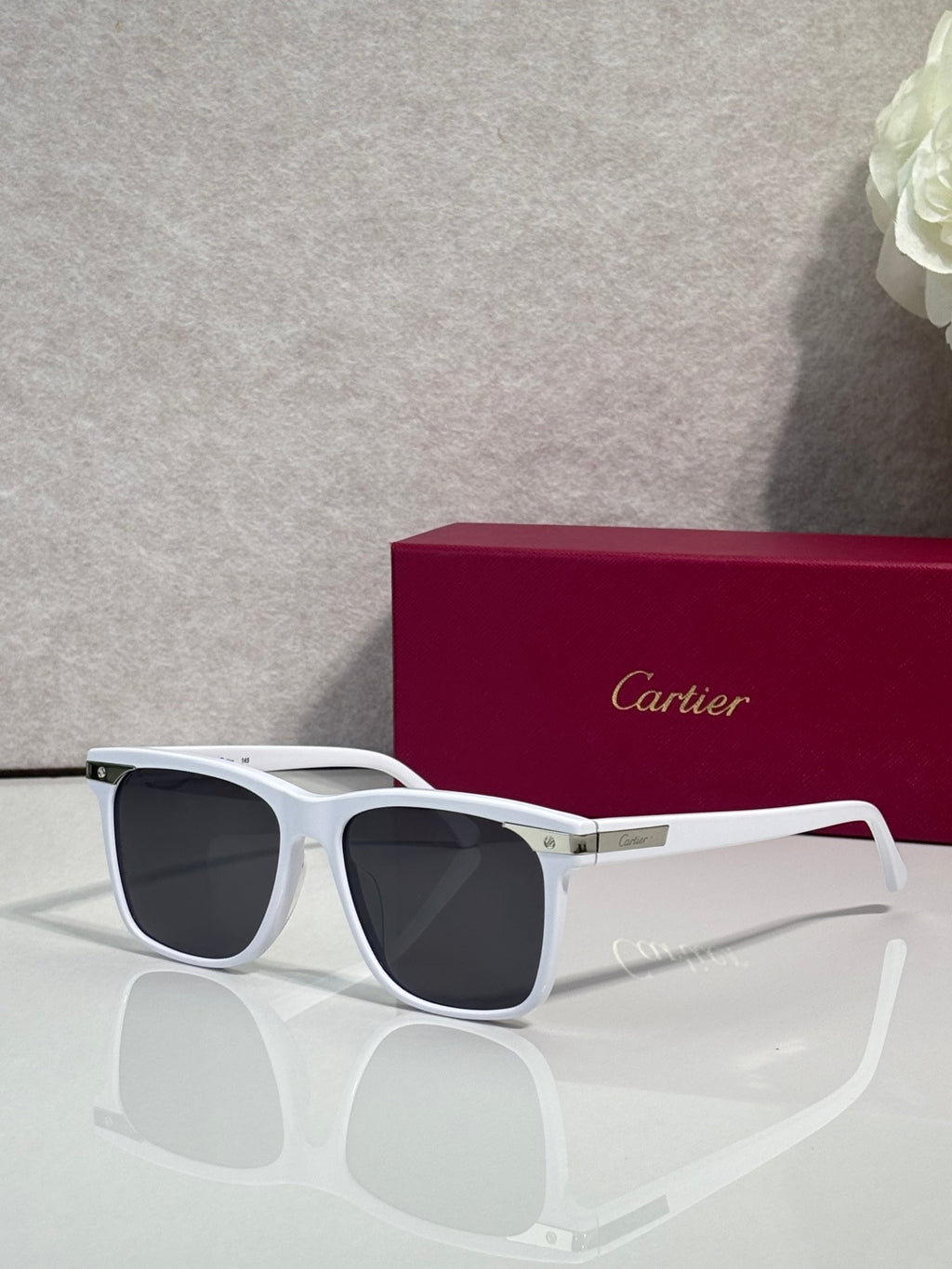 Sunglasses with white frames and dark lenses, gold hinge detail
