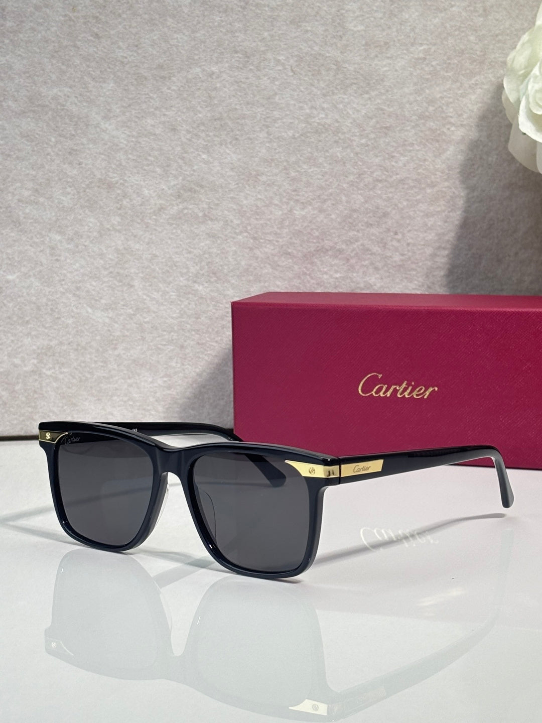 Sunglasses with dark frames, blue-tinged lenses, and gold hinge detail