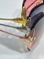 Louis Vuitton glasses close-up of gold emblem and pink-tinted lens with metal arm