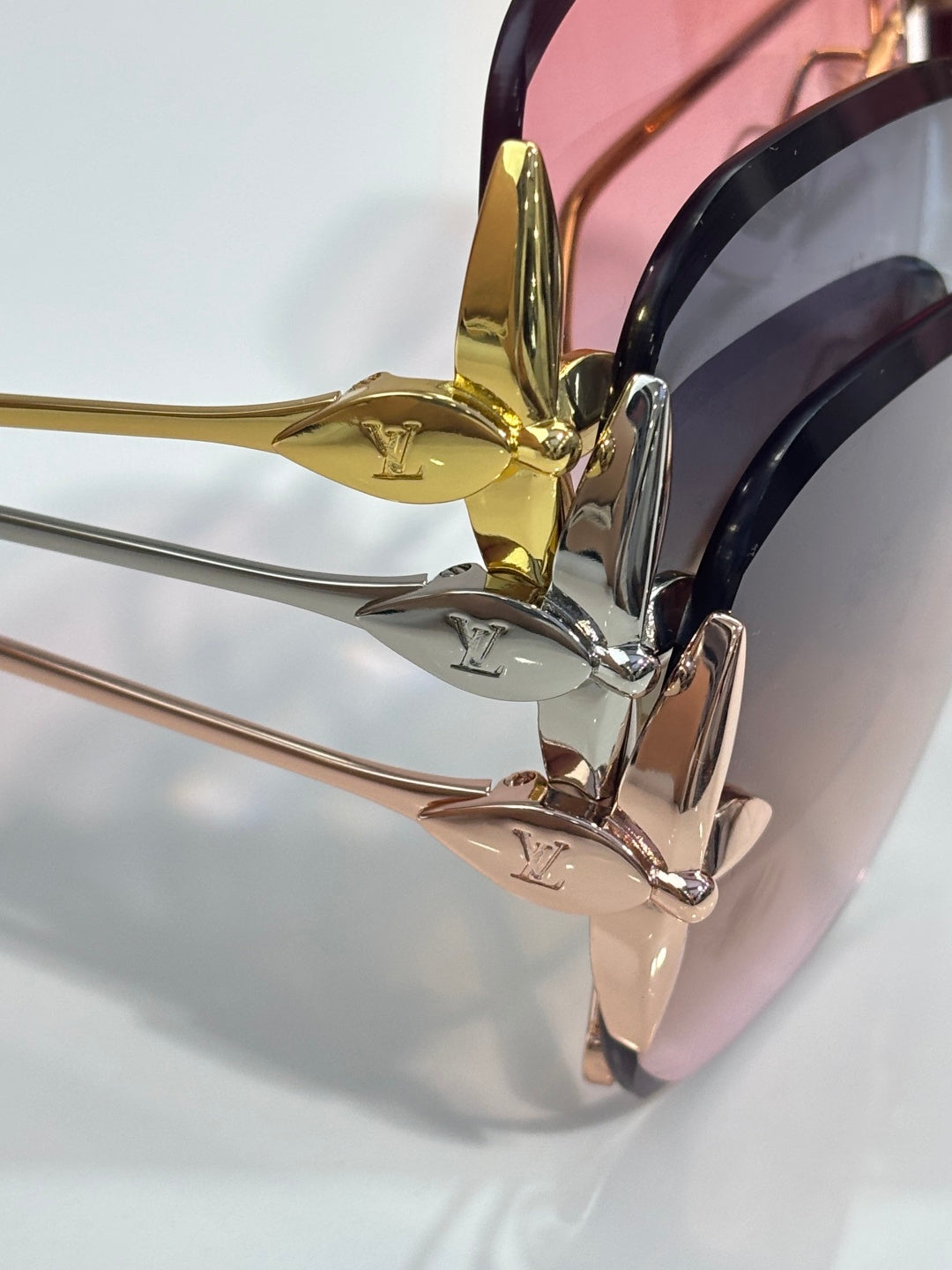 Louis Vuitton glasses close-up of gold emblem and pink-tinted lens with metal arm