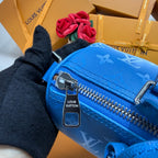 Blue monogram zip-top crossbody bag close-up with metal zipper pull and clasp.