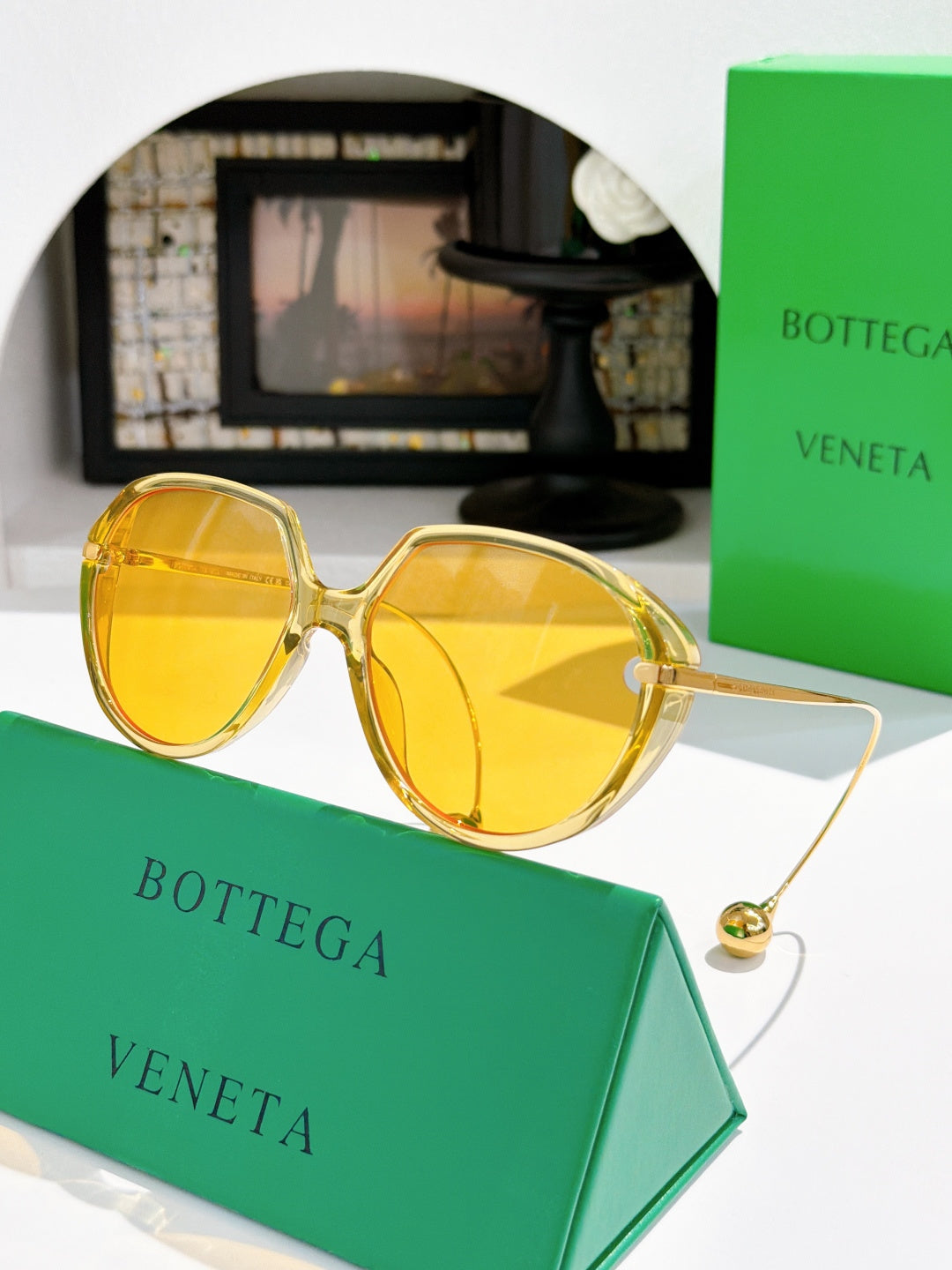 Bottega Veneta sunglasses with round tortoise frame and yellow lenses, gold accents.