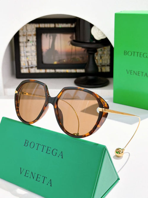 Bottega Veneta sunglasses with tortoise frame and amber lenses, slim gold temples.