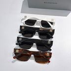 Assorted Balenciaga sunglasses stack: white, black, and brown frames with dark lenses
