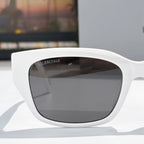 Balenciaga white sunglasses with dark tinted lenses, rounded cat-eye profile