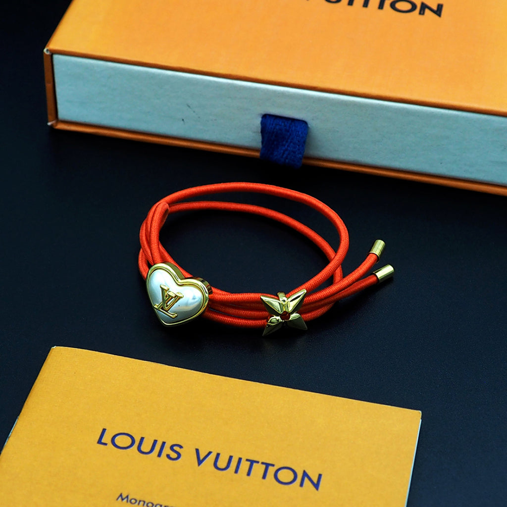 Louis Vuitton red cord bracelet with gold heart charm and gold bow centerpiece
