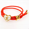 Louis Vuitton red cord bracelet with gold heart centerpiece and gold bow charm