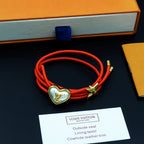 Louis Vuitton red cord bracelet with gold heart charm and gold bow charm