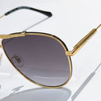 Louis Vuitton sunglasses close-up with gold frame and dark purple gradient lenses