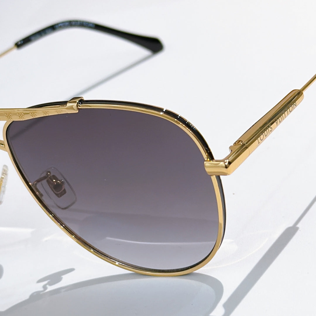 Louis Vuitton sunglasses close-up with gold frame and dark purple gradient lenses