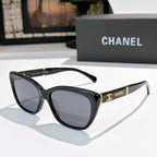 Black cat-eye sunglasses with dark lenses and gold Chanel logo on temple