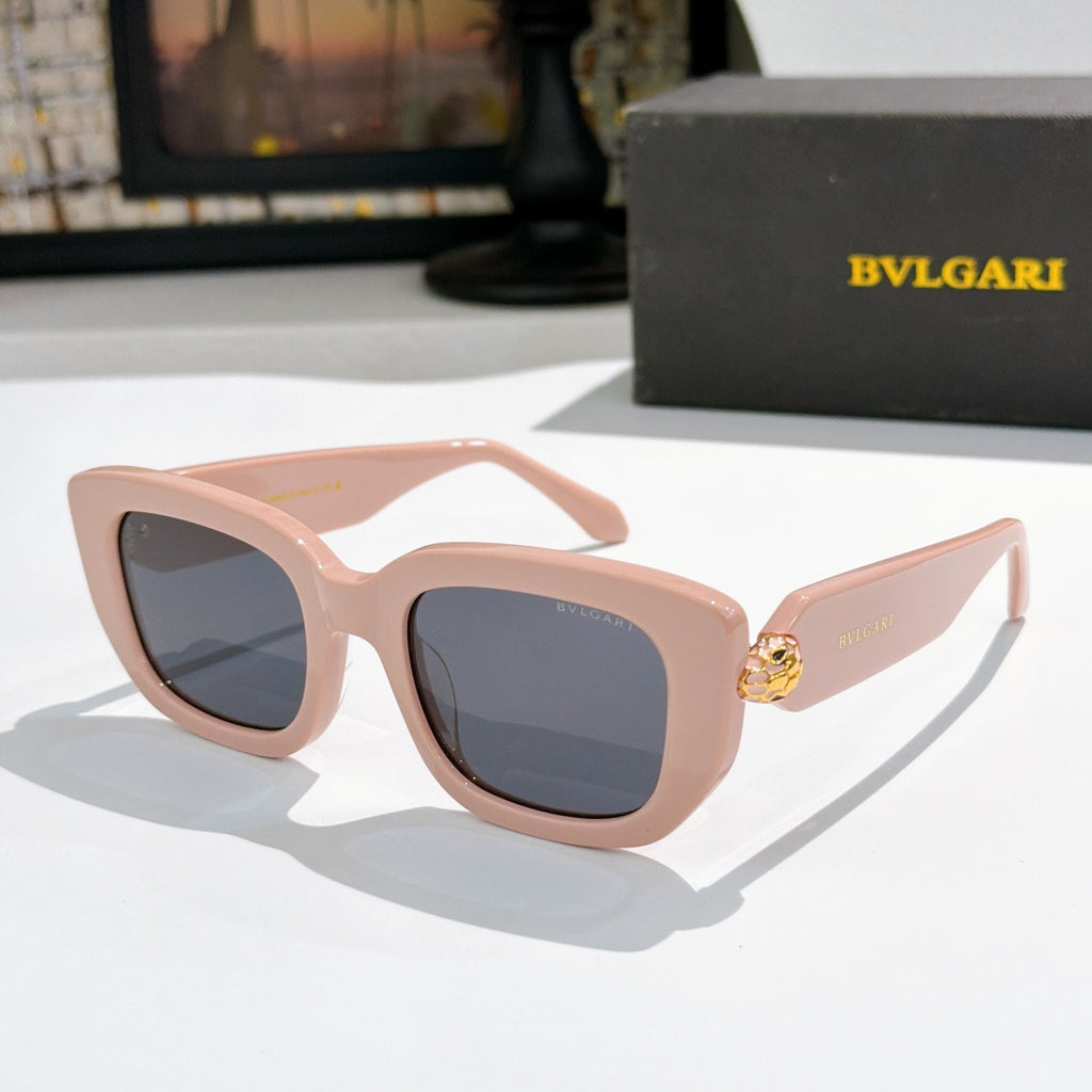 Pink cat-eye sunglasses with blue-gray lenses and gold logo bridge detail.