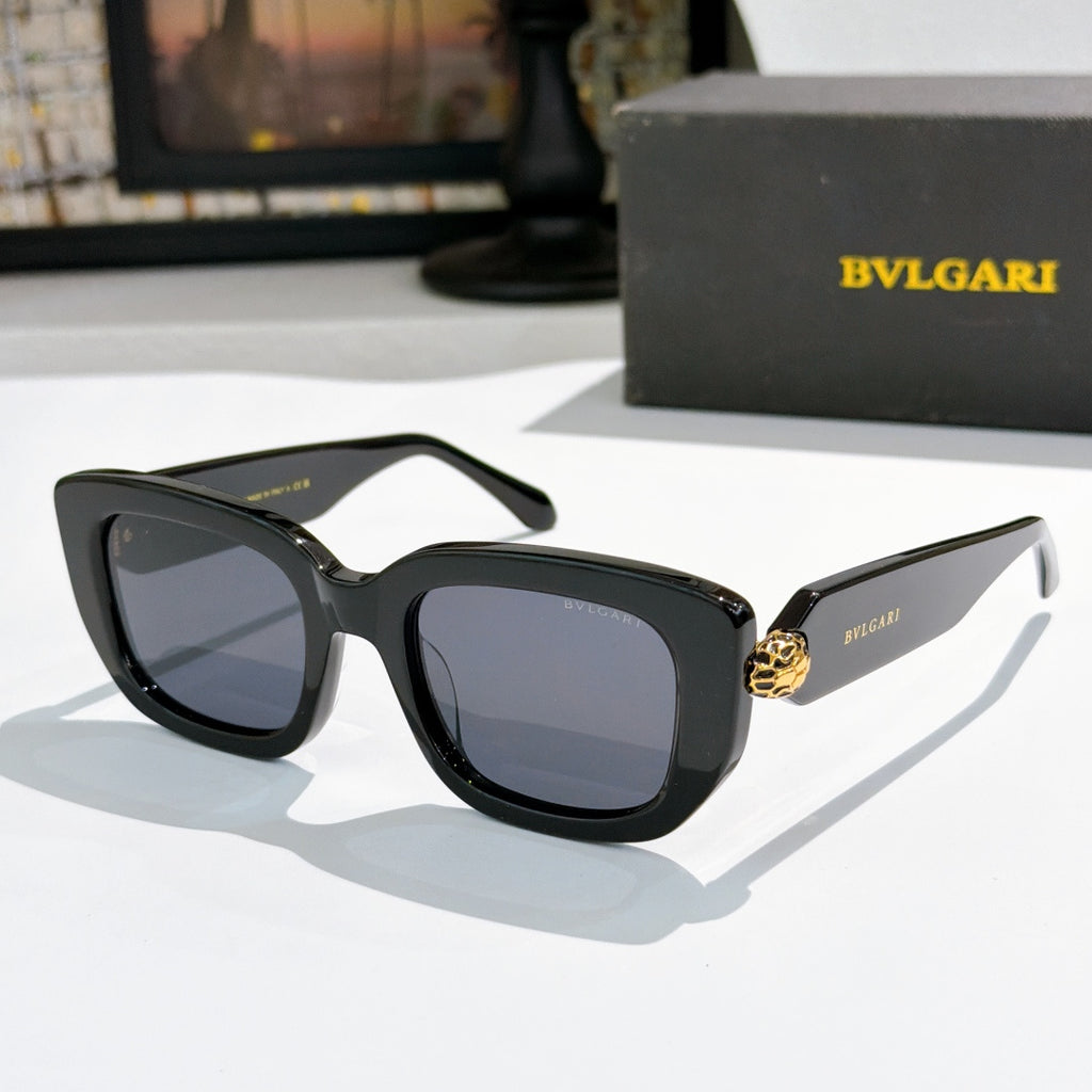 Black cat-eye sunglasses with blue-tinted lenses and gold logo bridge detail.