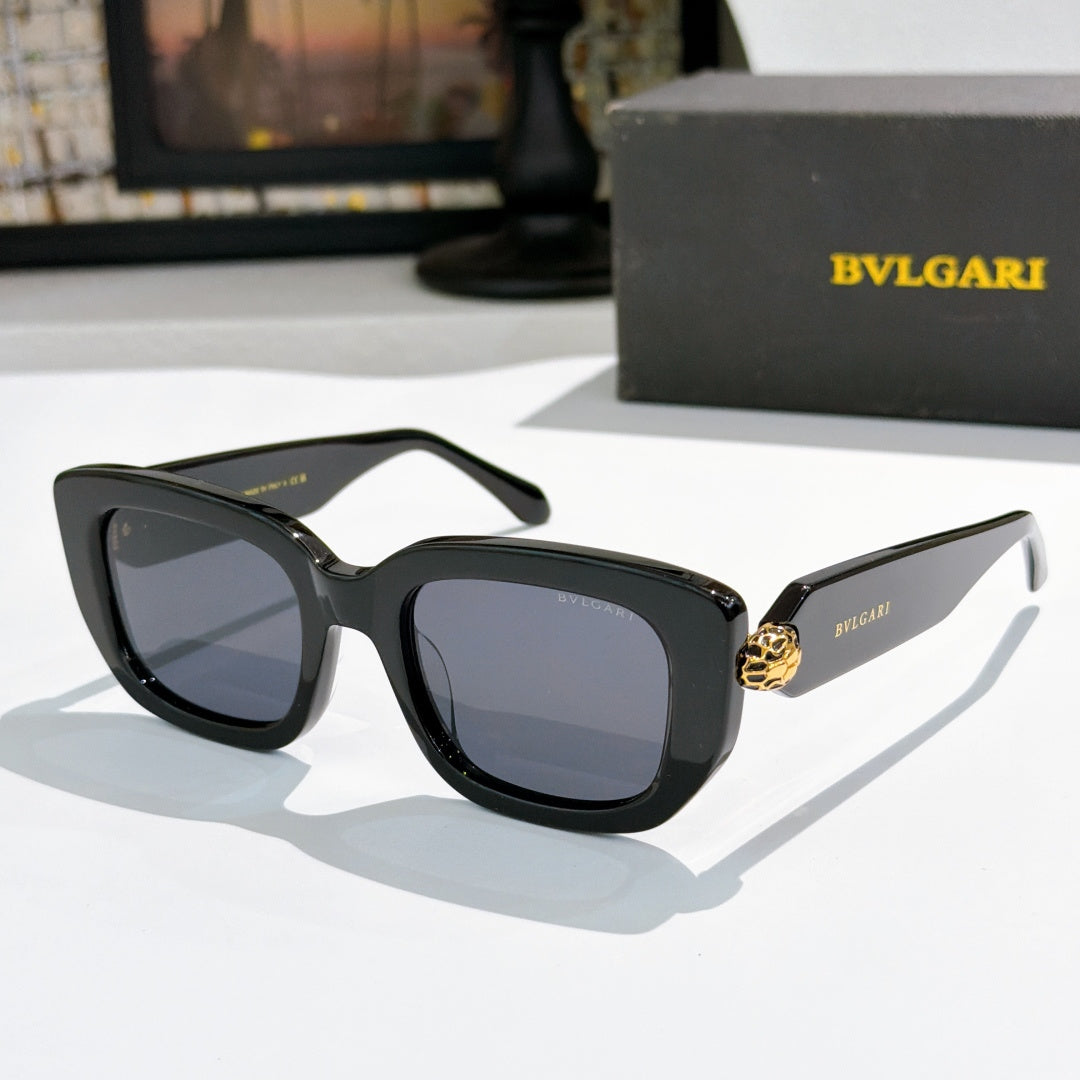 Black cat-eye sunglasses with blue-tinted lenses and gold logo bridge detail.