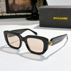 Black cat-eye sunglasses with light tan lenses and gold logo bridge detail.