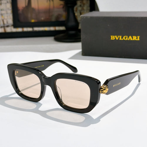 Black cat-eye sunglasses with light tan lenses and gold logo bridge detail.