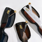Louis Vuitton sunglasses close-up with glossy black frames and gold logo temples.