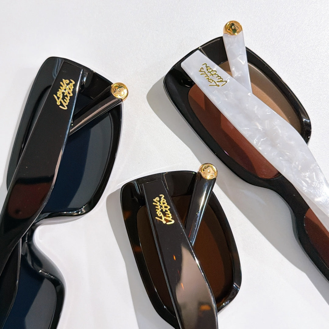 Louis Vuitton sunglasses close-up with glossy black frames and gold logo temples.