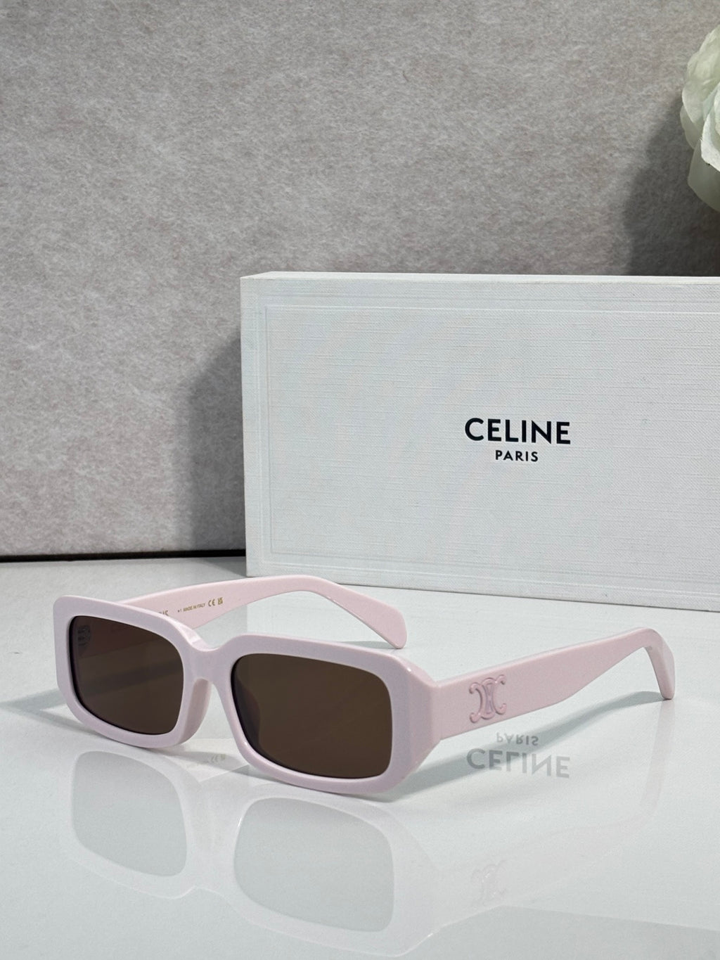 Celine sunglasses with white frame, pale pink temples, and dark lenses