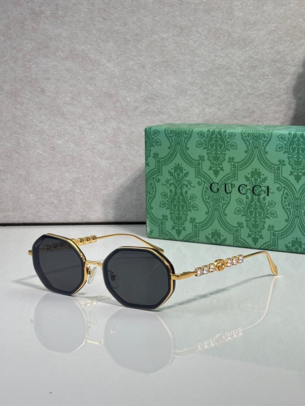 Gucci sunglasses, round dark lenses, gold-tone frame with chain detail on temples.
