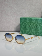 Gucci sunglasses, round blue gradient lenses, gold-tone frame with chain detail on temples.