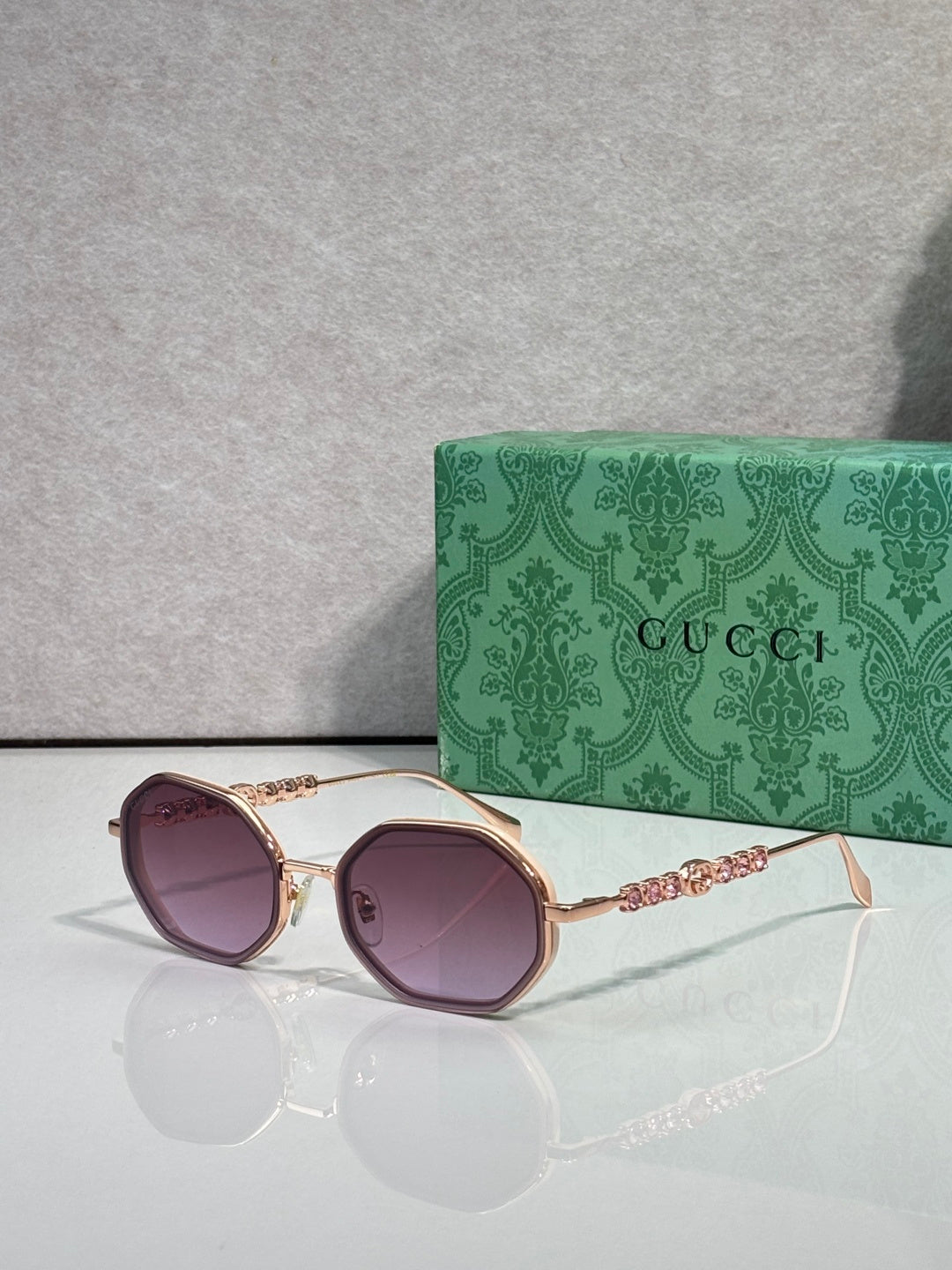 Gucci sunglasses, round purple lenses, gold-tone frame with chain and jeweled temple detail.