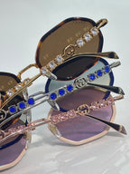 Gucci sunglasses close-up, round frames with jeweled bars and blue stone temple accents.