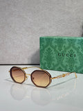Gucci sunglasses, round dark-tan lenses, gold-tone frame with chain detail on temples.