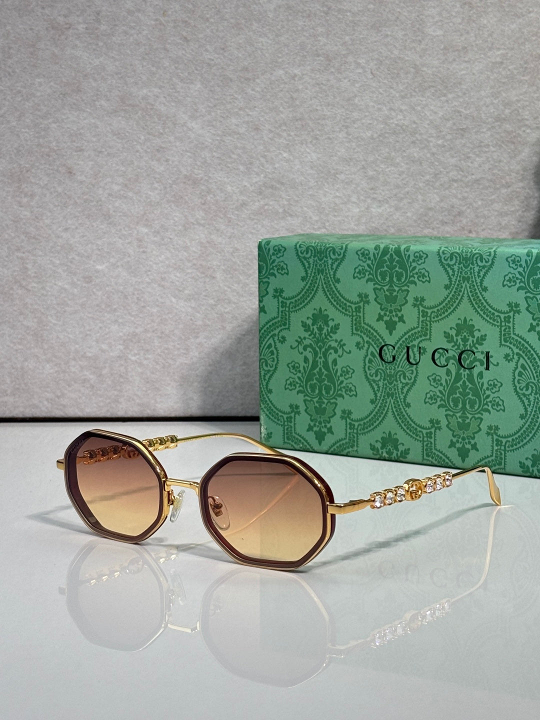 Gucci sunglasses, round dark-tan lenses, gold-tone frame with chain detail on temples.