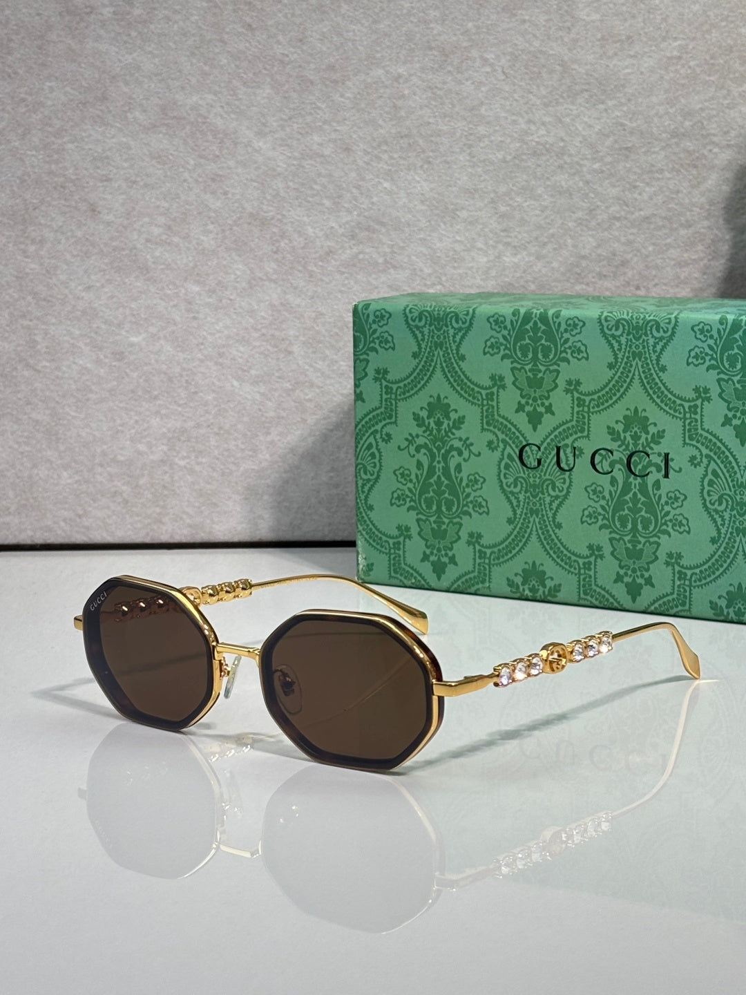 Gucci sunglasses, round dark-brown lenses, gold-tone frame with chain detail on temples.