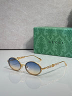 Gucci round sunglasses with gold-tone frame and light blue lenses.