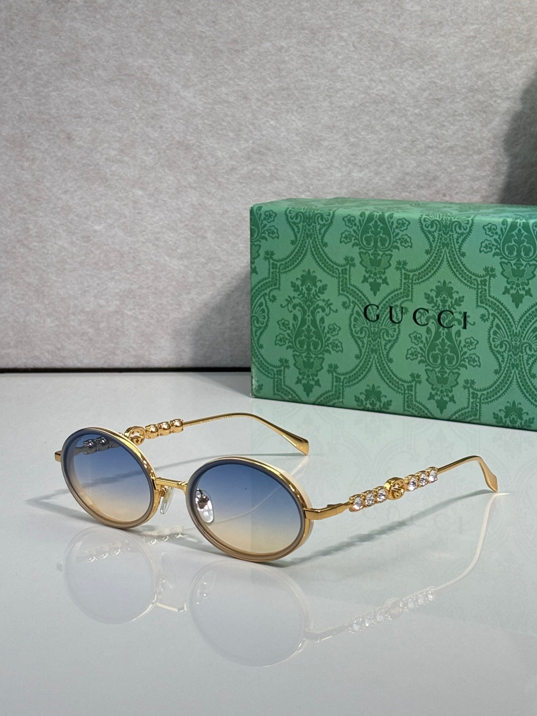Gucci round sunglasses with gold-tone frame and light blue lenses.